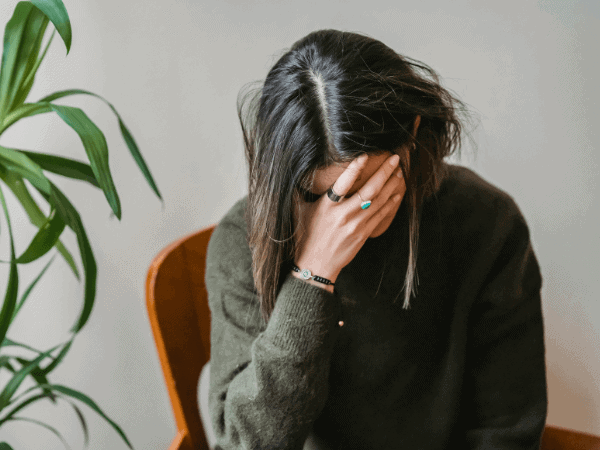 A woman resting her hands on her face while sitting, lost in thought about discovering her life purpose through astrology.