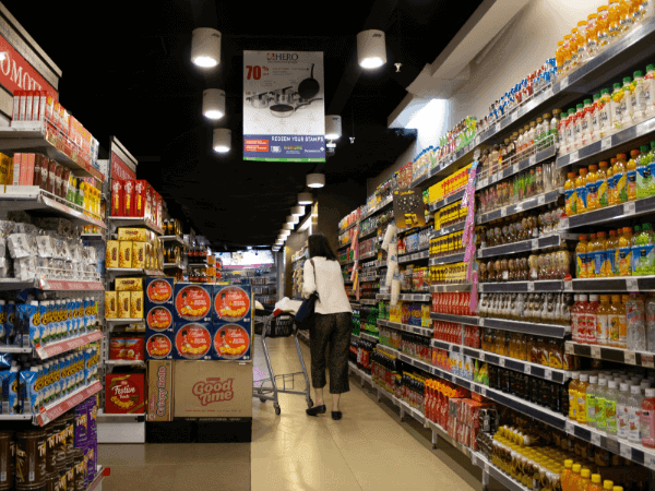 A woman in a supermarket aisle examining products on the shelves