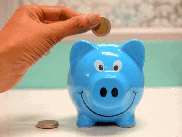 A hand depositing a coin into a piggy bank, illustrating the financial struggles encountered during the first business attempt.