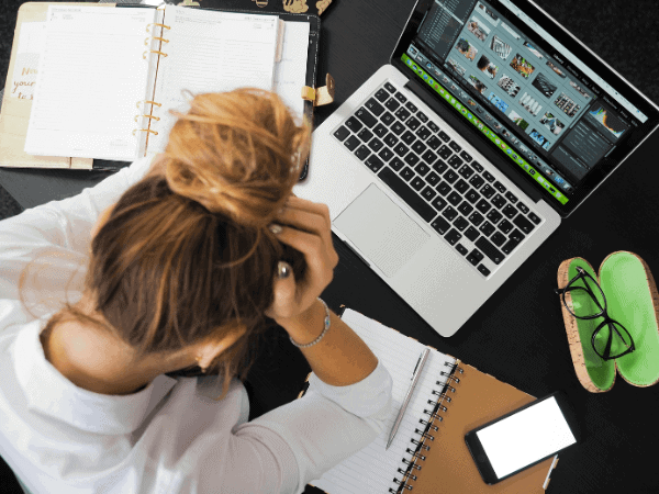 A woman sits at her desk with a laptop and coffee, reflecting on the reasons for her first business failure.