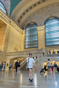 A woman is positioned in the heart of Grand Central Station, showcasing the grandeur of the iconic Midtown building.