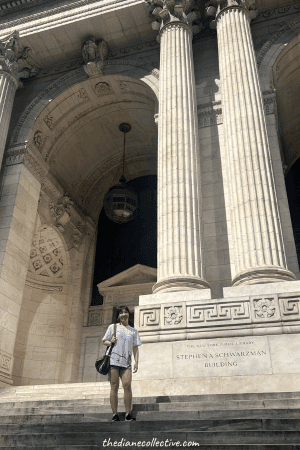 A woman stands on the steps of the New York City Public Library in Midtown.