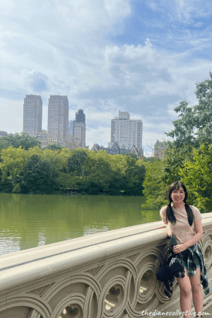 A woman relaxes on Bow Bridge to enjoy the view of the lake in Central Park, NYC