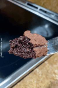 A close-up of a fork with a decadent piece of chocolate cake, highlighting its moist layers and glossy frosting